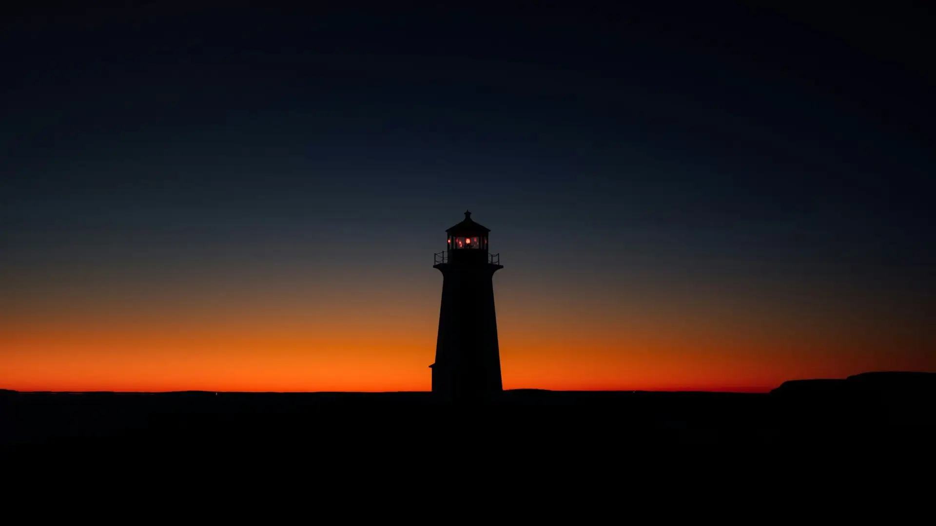 A lighthouse in silhouette against an amber sunset